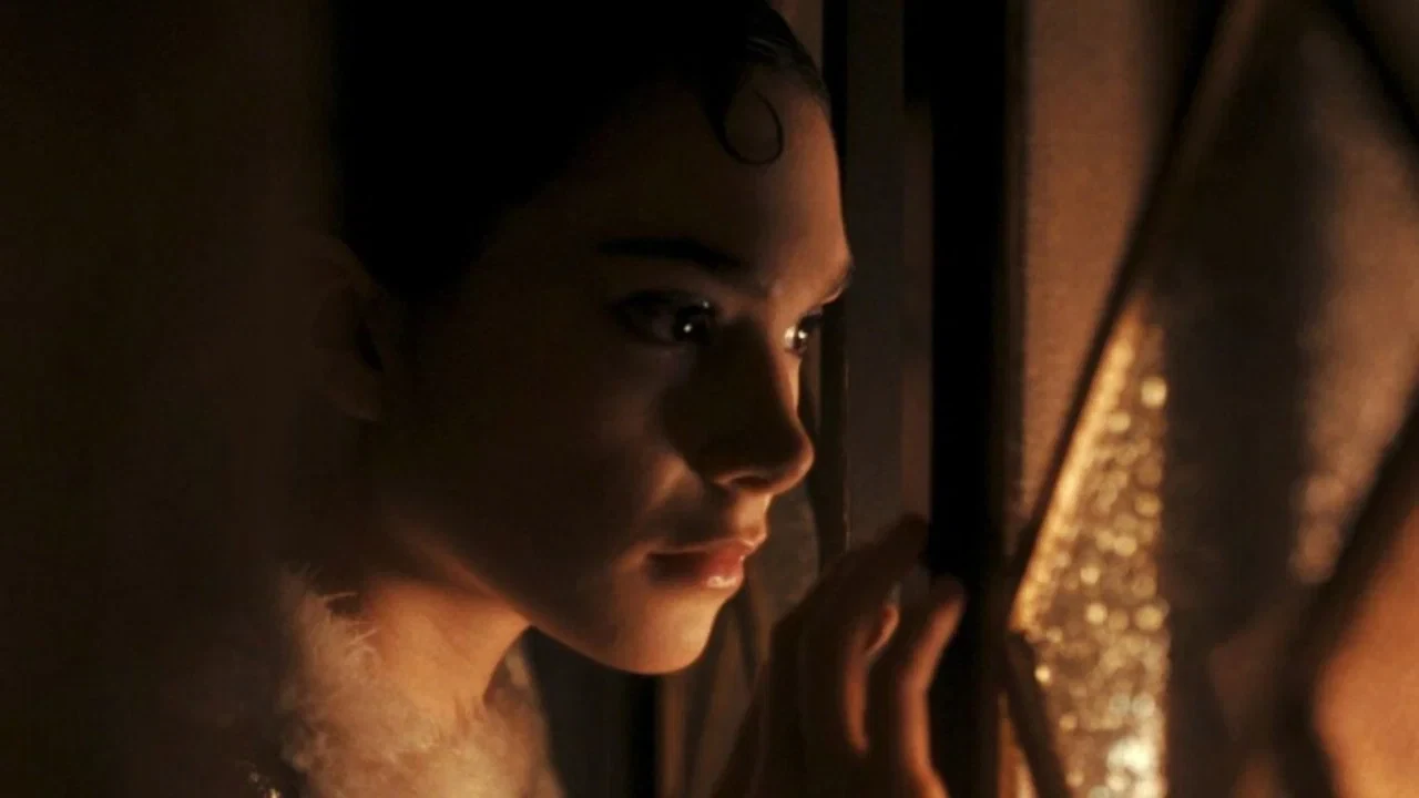 لقطة قريبة لوجه فتاة تراقب خلف شق مضاء بضوء كهرماني.