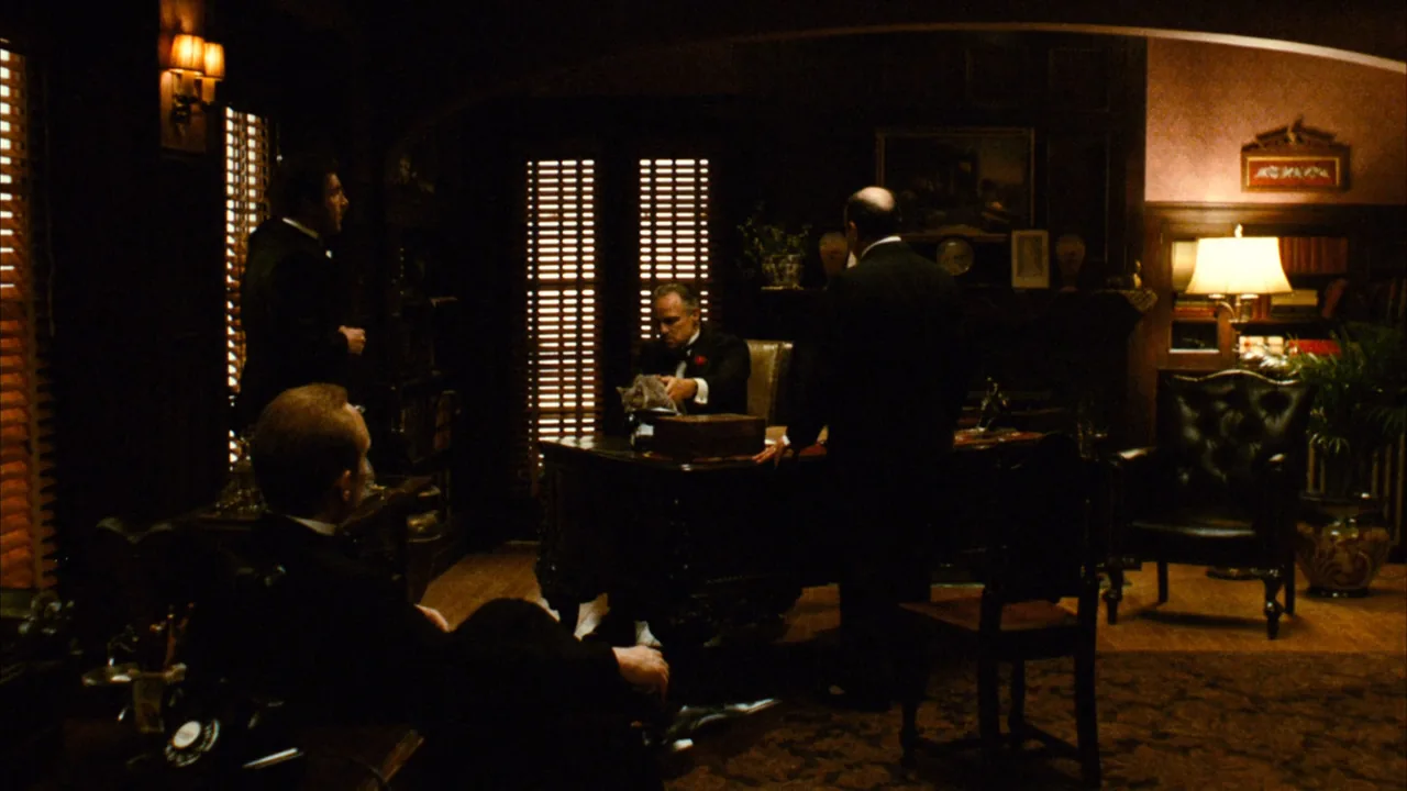 مكتب فيتو كورليوني في The Godfather: الضوء المحدود والظلال والأثاث تجعل السلطة تبدو مغلقة على عالمها.
