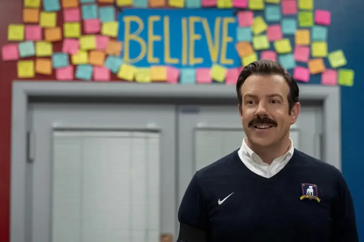 تيد يقف أمام باب أسفل لافتة Believe