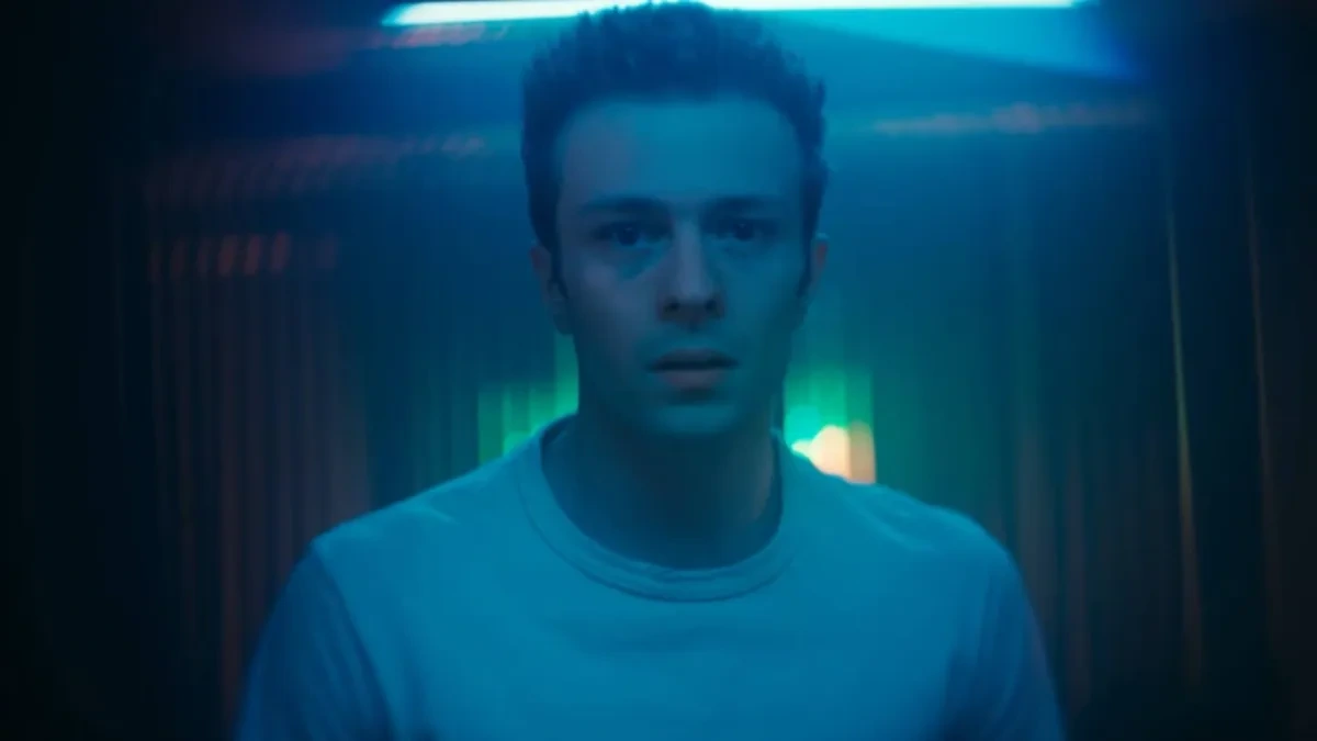 لقطة قريبة لتومي وسط إضاءة زرقاء وخلفه مصابيح ملونة.